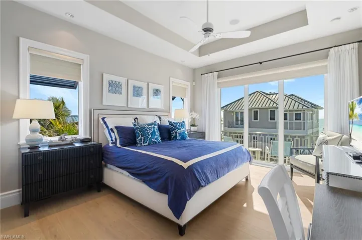 Primary Bedroom with access to outside, light wood-type flooring, a raised ceiling, and a ceiling fan