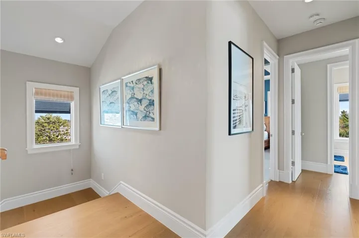 Hall featuring light wood finished floors, baseboards, and a wealth of natural light