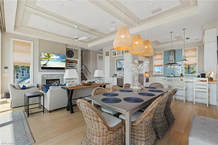 Dining room featuring stairway, light wood-style floors, a tray ceiling, and visible vents