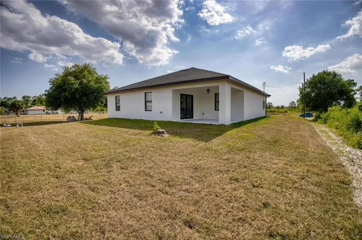 Back of house with a yard and a patio