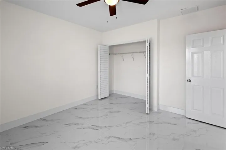 Unfurnished bedroom with ceiling fan, a closet, and light tile flooring