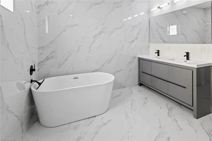 Bathroom with tile flooring, large vanity, and tile walls