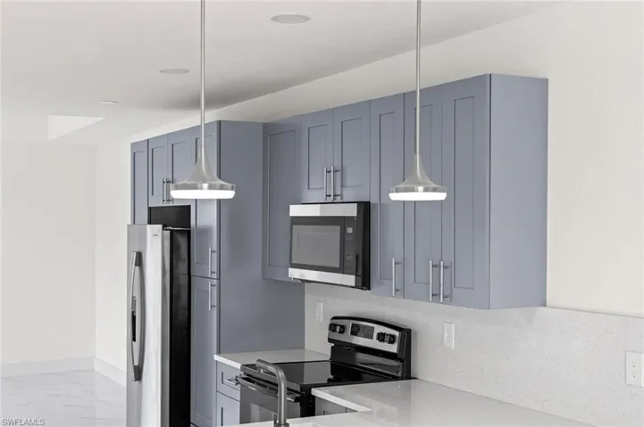 Kitchen featuring decorative light fixtures, stainless steel appliances, light stone counters, and tasteful backsplash