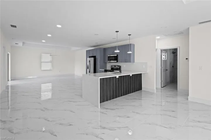 Kitchen featuring stainless steel appliances, pendant lighting, light tile floors, and kitchen peninsula