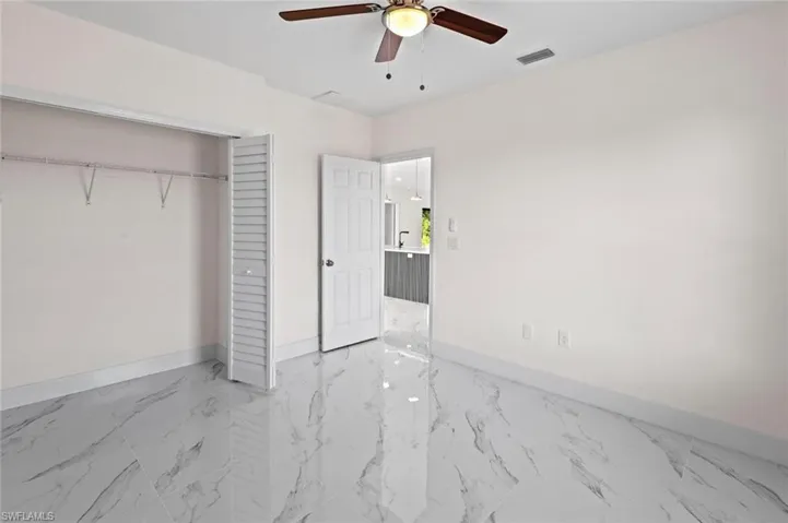 Unfurnished bedroom featuring a closet, light tile flooring, and ceiling fan