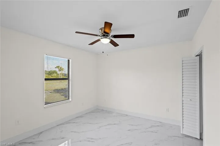Unfurnished room with ceiling fan and light tile floors