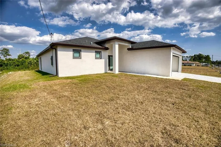 Rear view of house featuring a garage and a lawn
