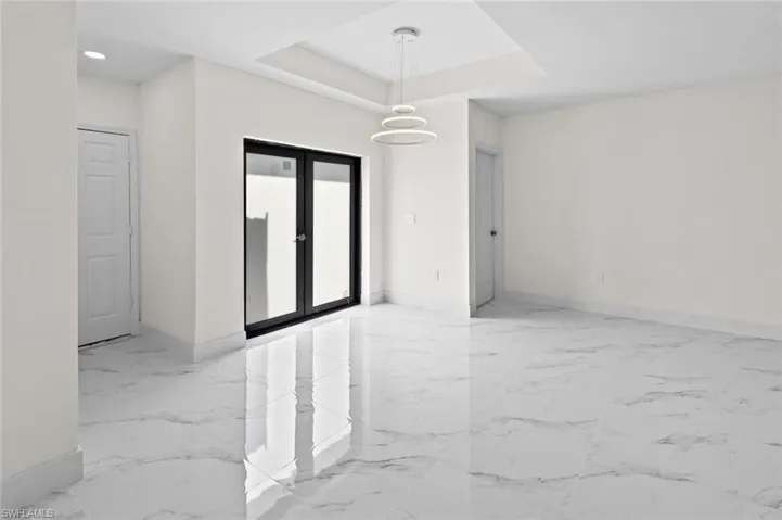 Spare room featuring a tray ceiling and light tile floors