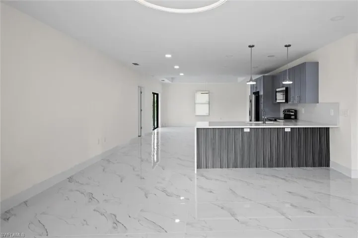 Kitchen featuring hanging light fixtures, stainless steel appliances, kitchen peninsula, sink, and light tile floors