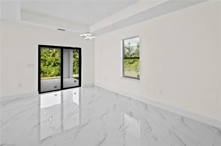 Empty room with a raised ceiling and light tile flooring