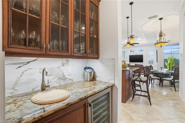 The wet bar area is ideally located off of the kitchen with a new beverage/wine cooler, and custom glass cabinetry