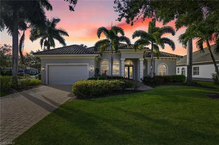 Mediterranean / spanish home with decorative driveway, stucco siding, a front lawn, an attached garage, and a tile roof