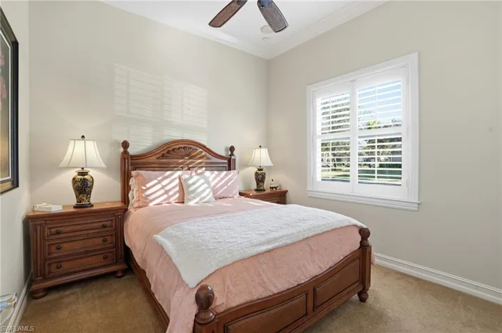 This guest room features high ceilings, crown molding, and plantation shutters