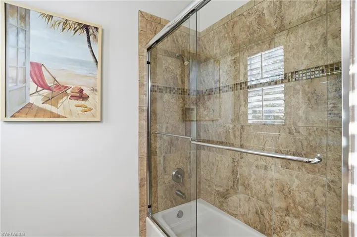 Bathroom with enclosed tub / shower combo and plenty of natural light