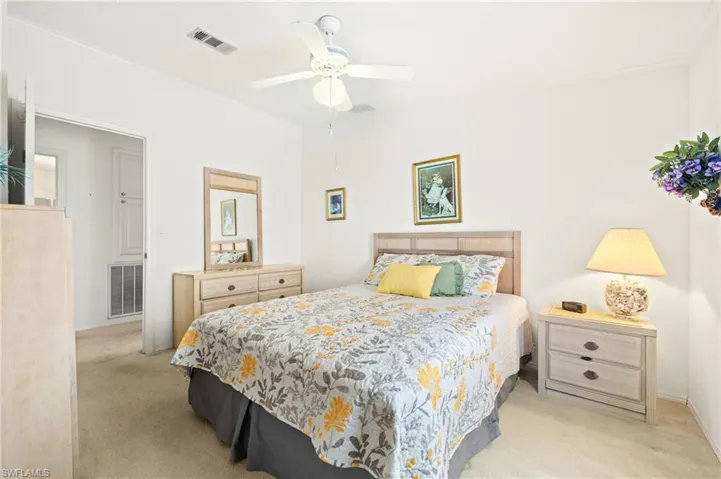 Bedroom featuring light carpet, baseboards, visible vents, and ceiling fan
