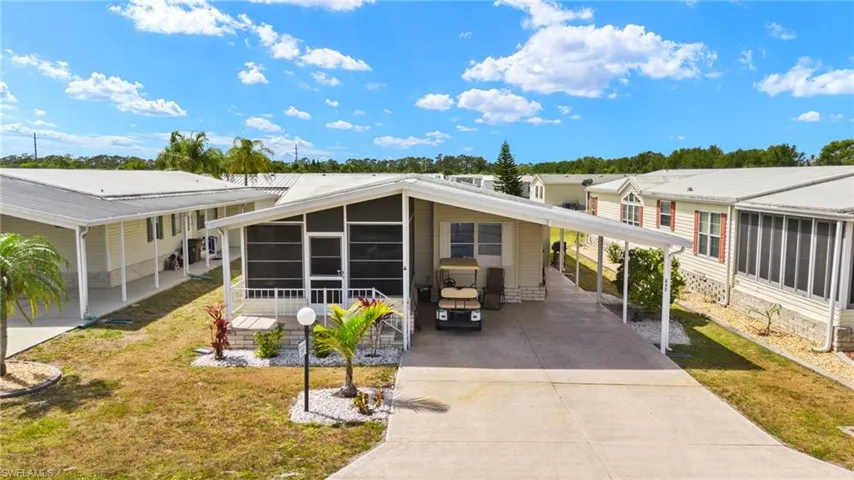 View of front of property featuring a sunroom, a carport, driveway, and a front yard
