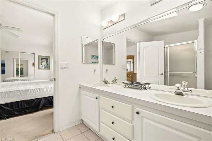 Ensuite bathroom featuring a shower stall, tile patterned floors, a sink, double vanity, and ensuite bath