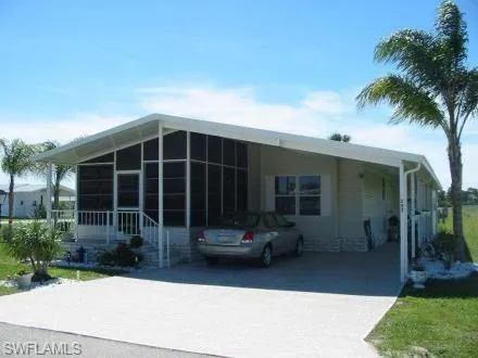 Manufactured / mobile home featuring a sunroom, concrete driveway, and an attached carport