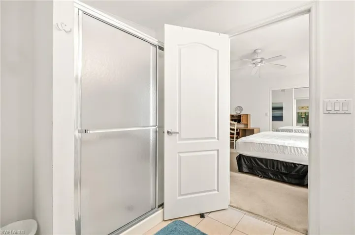 Ensuite bathroom with ceiling fan, tile patterned flooring, a stall shower, and ensuite bathroom