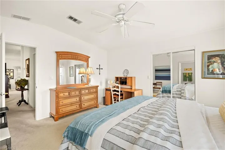 Bedroom featuring lofted ceiling, light colored carpet, visible vents, and a ceiling fan