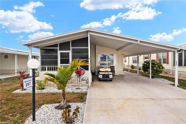 Manufactured / mobile home with a sunroom, a carport, and driveway