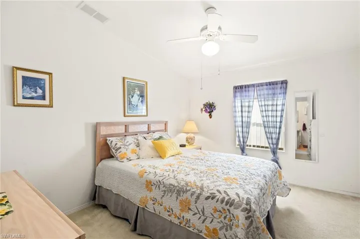 Bedroom with a ceiling fan, carpet floors, lofted ceiling, and visible vents