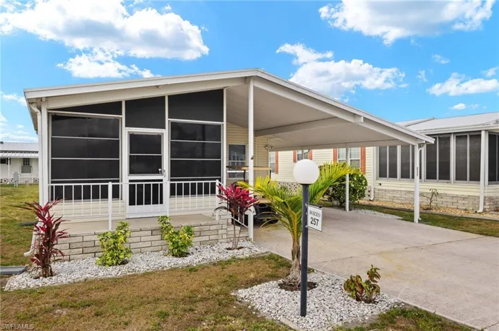 Manufactured / mobile home featuring a carport, a sunroom, and concrete driveway