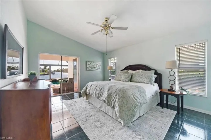 Tiled bedroom featuring baseboards, lofted ceiling, and ceiling fan.  The Master bedroom as sliders that open out to the pool and the beautiful view.  What a way to wake up!
