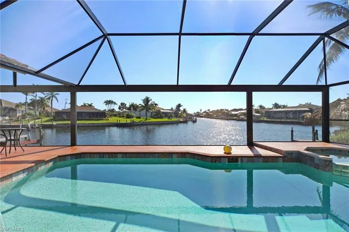 View of swimming pool featuring a pool with connected hot tub, a water view, glass enclosure, and a patio