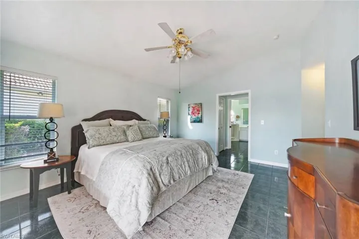 Bedroom with baseboards, lofted ceiling, dark tile patterned floors, and a ceiling fan