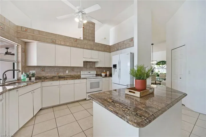 Kitchen with white appliances, light tile patterned floors, decorative backsplash, a sink, and a ceiling fan