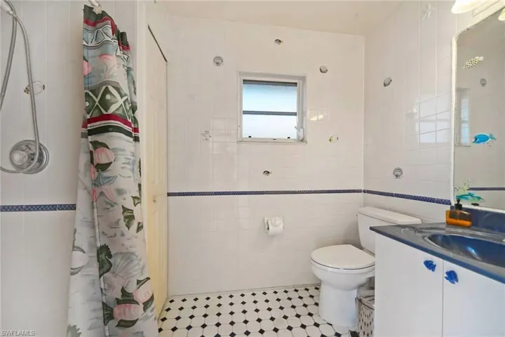 Pool bathroom featuring tile walls, vanity, toilet, and tiled shower