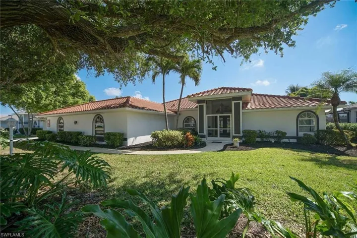 Mediterranean / Spanish house with a front lawn, a tile roof, and stucco siding. Lovely entrance with side garage