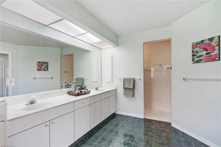 Full bath featuring baseboards, double vanity, a sink, and walk in shower