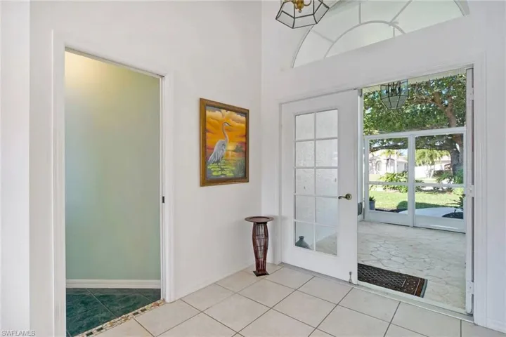 Foyer with light tile patterned flooring, a notable chandelier, and baseboards