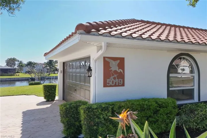 View of home's exterior featuring a tiled roof, stucco siding, a water view, and a garage