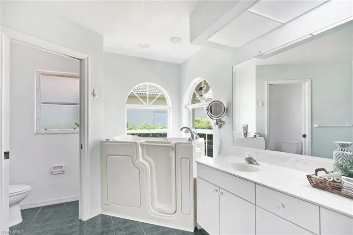 Full bathroom featuring a bathing tub, baseboards, toilet, vanity, and tile patterned flooring