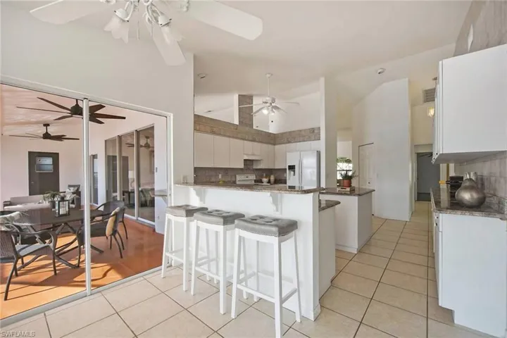Kitchen with light tile patterned flooring, ceiling fan, and white appliances