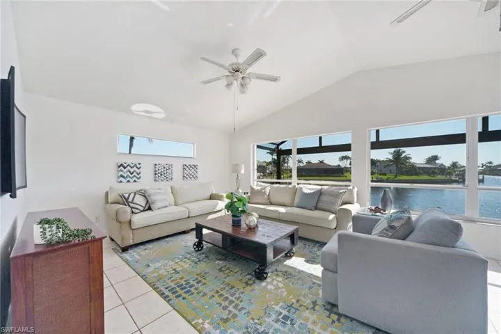 Living area with lofted ceiling, a ceiling fan, a water view, and light tile patterned floors.  What a view!!!