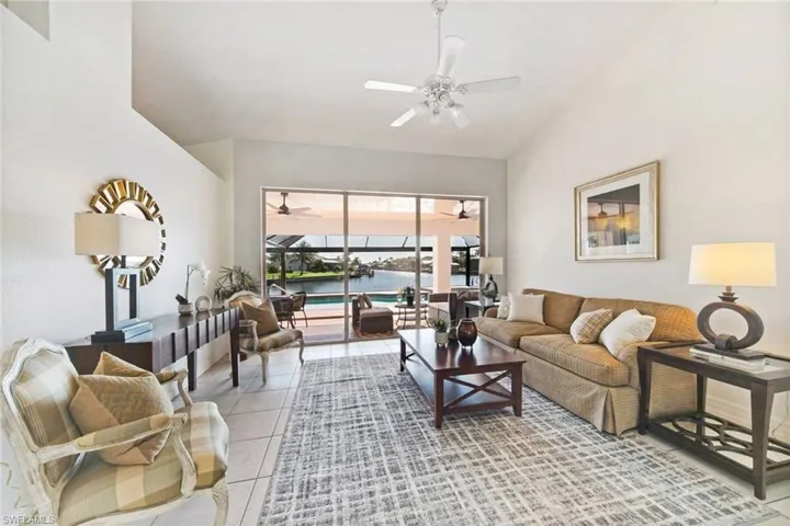 Living room featuring light tile patterned flooring, high vaulted ceiling, a water view, and ceiling fan.  this has that WOW factor when you walk in and you will fall in love with the home.