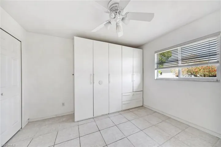 Unfurnished bedroom featuring light tile floors, baseboards, and ceiling fan  One of four bedrooms!