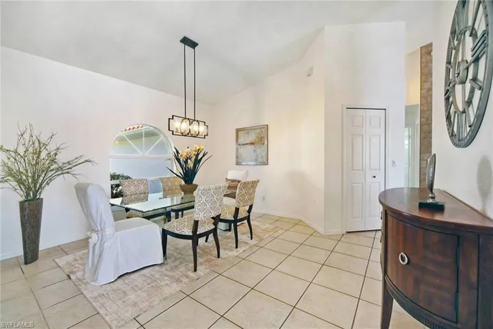 Dining area with baseboards, high vaulted ceiling, an inviting chandelier, and light tile patterned floors.  Beautiful, ight dining room for making family memories.