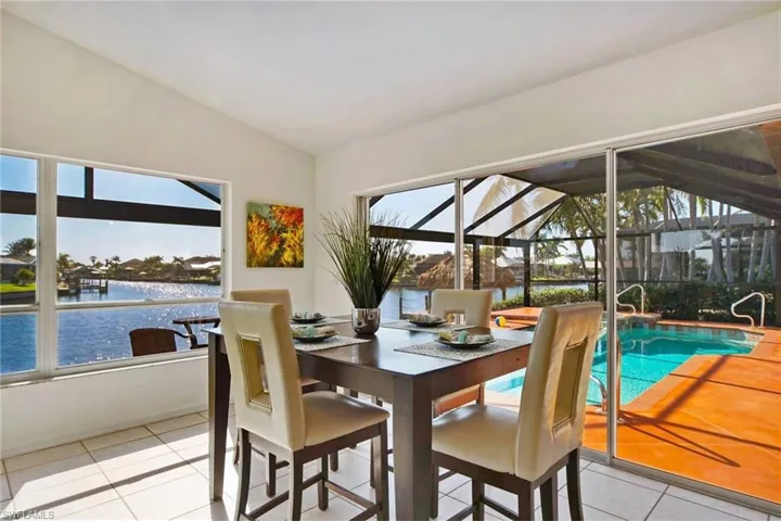 Tiled dining space with lofted ceiling and a water view