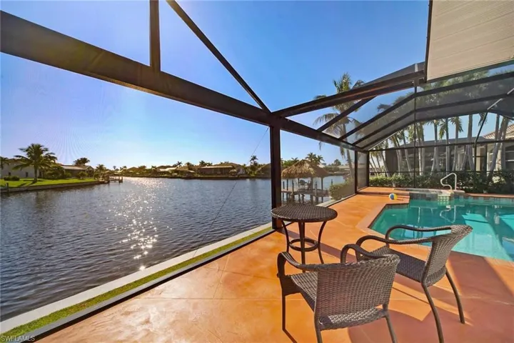 Pool with glass enclosure, a water view, and a patio area