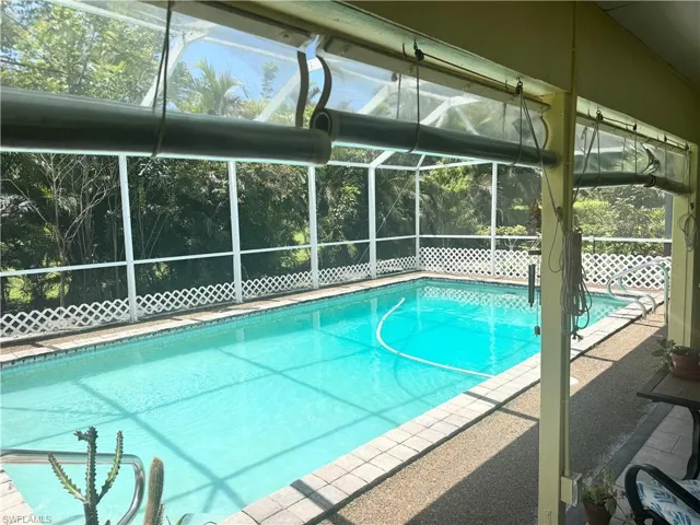 Swimming pool featuring glass enclosure and a patio