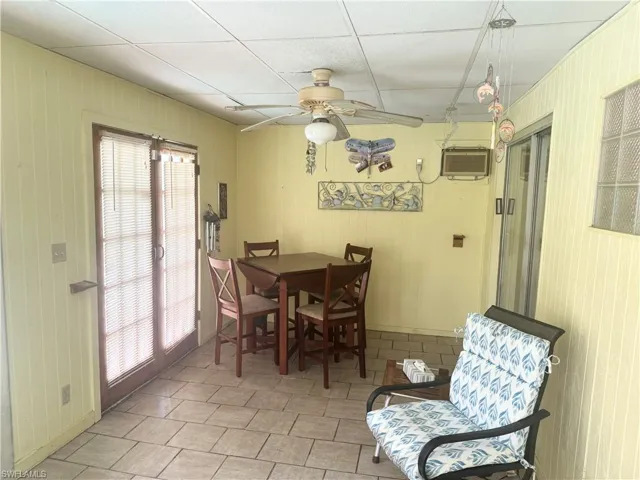Dining space with a wall mounted AC, a ceiling fan, and wooden walls