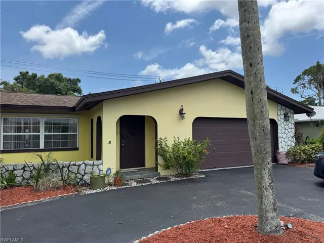 View of front of home with an attached garage, stucco siding, and asphalt driveway