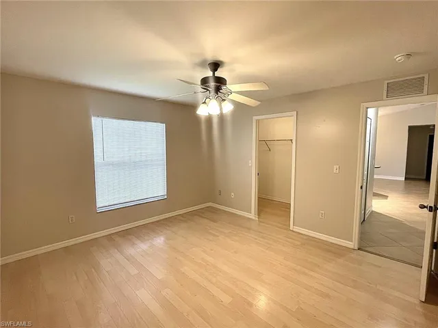 Unfurnished bedroom featuring ceiling fan, a closet, light wood-type flooring, and a spacious closet