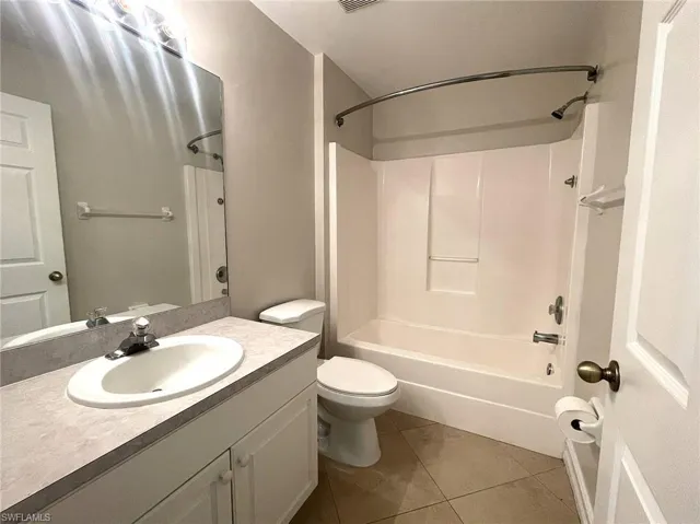Full bathroom with shower / washtub combination, tile patterned floors, toilet, and vanity