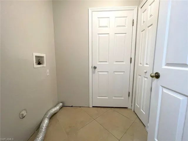 Washroom with light tile patterned flooring and hookup for a washing machine
